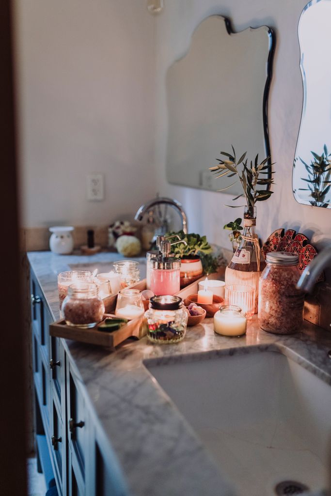 Warm bathroom countertop featuring candles and skincare products for a serene ambiance winter shower routine