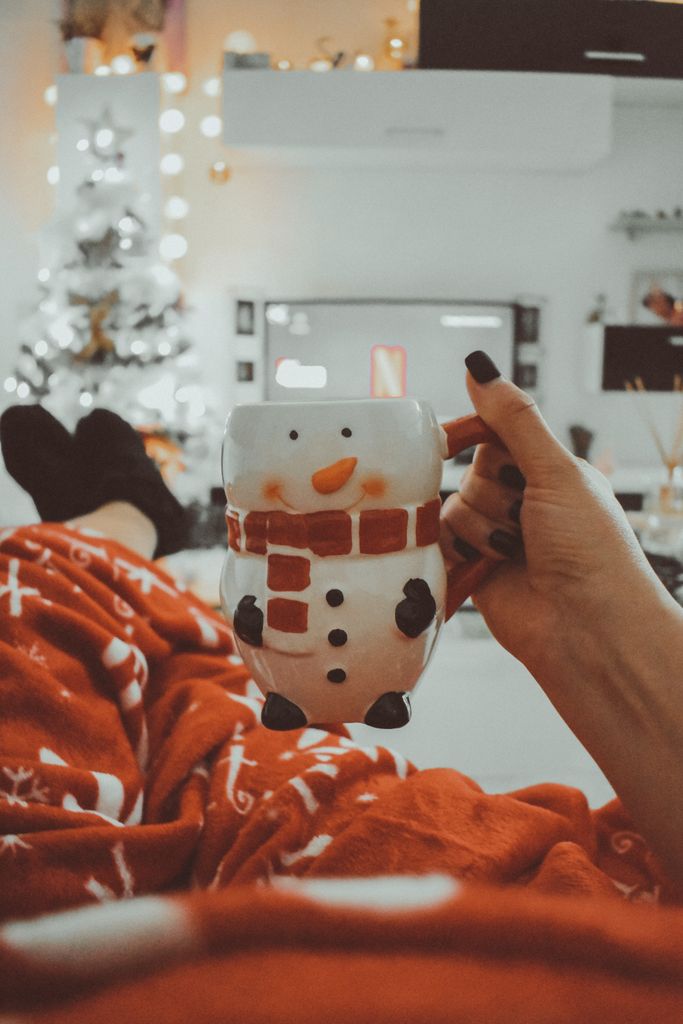 Warm indoor winter scene with snowman mug and festive Christmas decor.