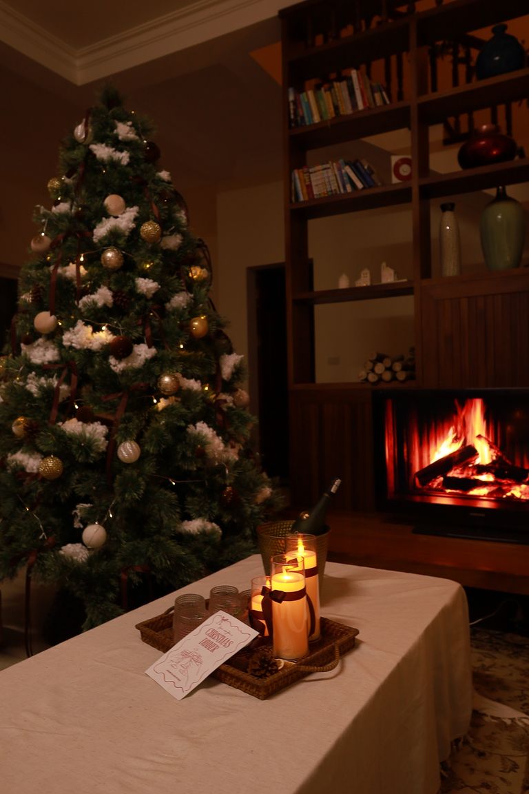 Warm living room with decorated Christmas tree, fireplace, and candles setting a festive mood.
