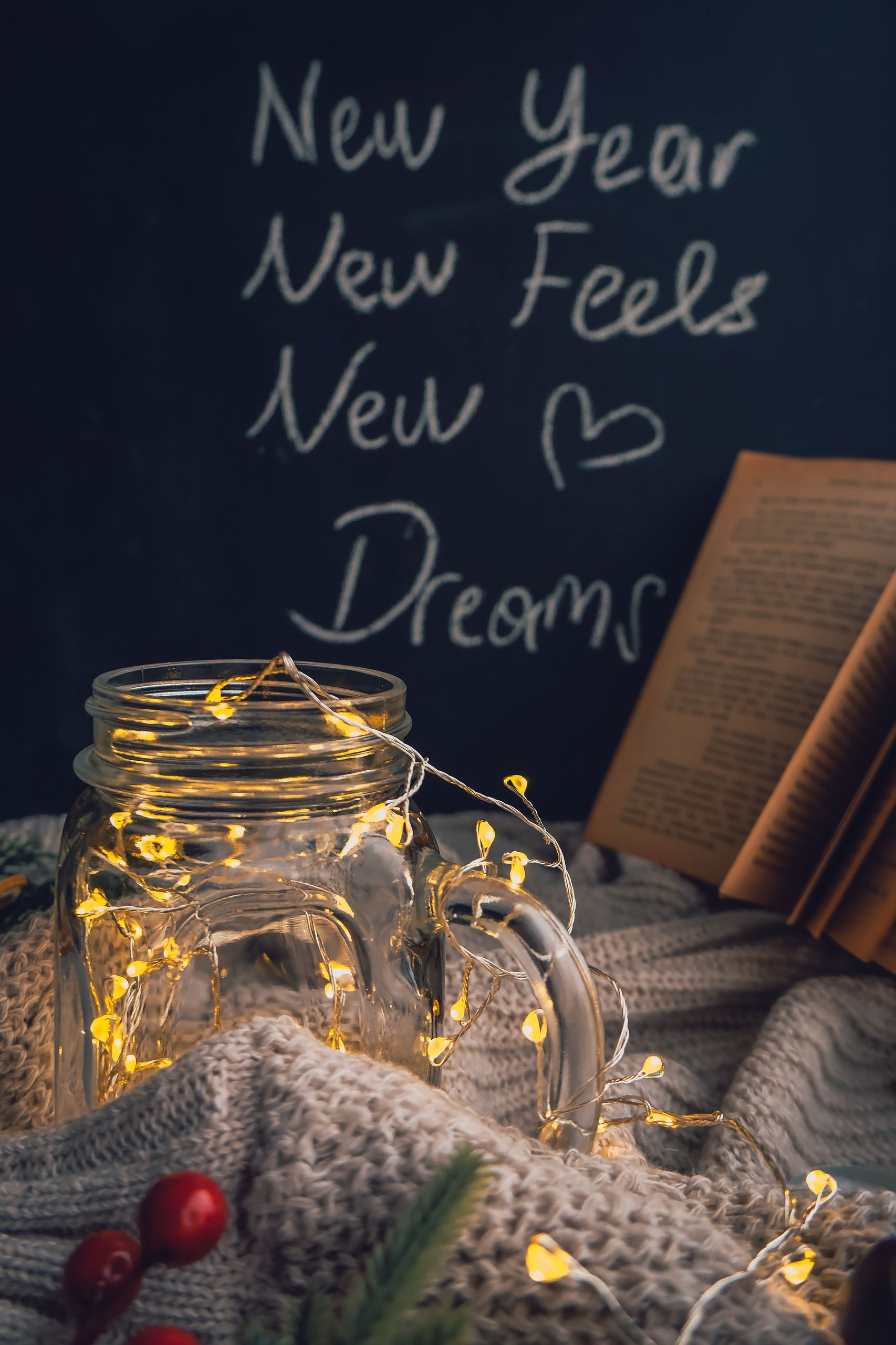 Warm New Year ambiance with fairy lights in a jar, book, and cozy blankets, inspiring dreams.