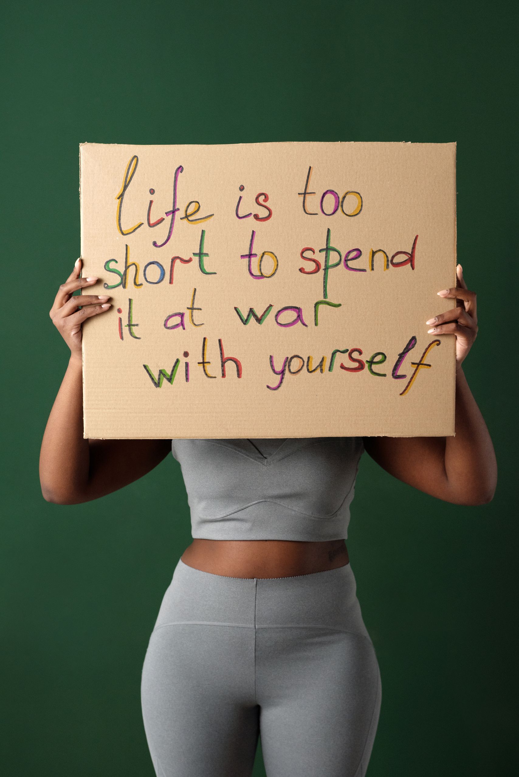 Woman holding a placard with motivational message against green background.